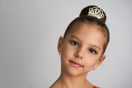 Cute little girl in orange dress posing over white background. Little princess girl portraitの写真素材