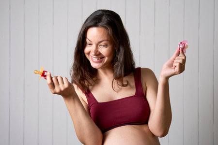Boy or girl, Pregnant woman holding baby pacifier. Pregnancy, motherhood, people and expectation...