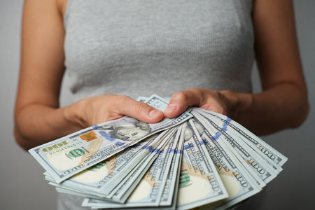 Woman holding money, close-up. Hands with paper money bills . Woman hands with hundred dollar...