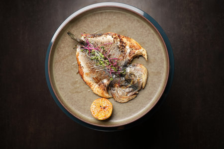 Fried dorado fish on a plate. Whole grilled spicy fish served for dinner on restaurant table