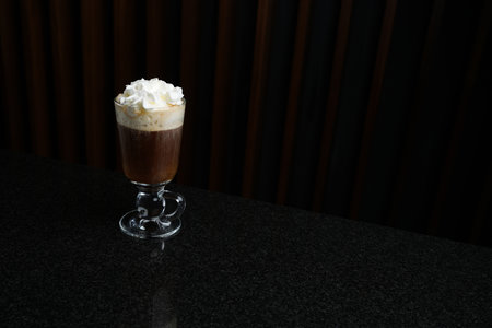 Glass of Viennese coffee topped with whipped cream, close-up on black marble table. Irish coffee...