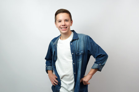 Portrait of teenage boy wearing denim shirt standing looking camera with smile, white background with copy spaceの写真素材
