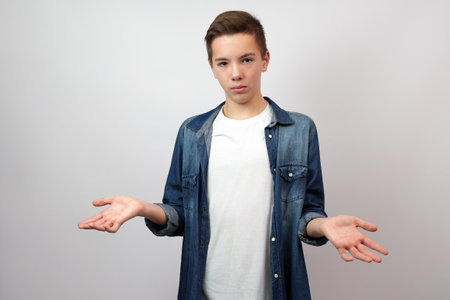 School boy confused with open arms, no idea concept, white background with copy spaceの写真素材