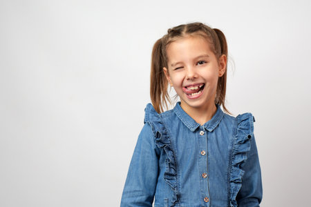 Cute little girl in denim dress posing over white background with copy space, close-upの写真素材
