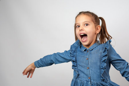 Cute happy girl pointing finger in copy space isolated on white backgroundの写真素材