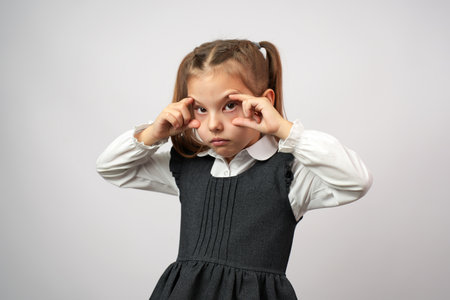 Cute girl tired trying to open eyes with fingers isolated on a white backgroundの写真素材