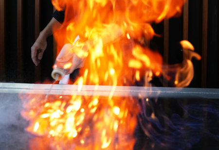 Chef cooking at stove with fire flame, close-up, selective focus. Chef cook food with fire at...