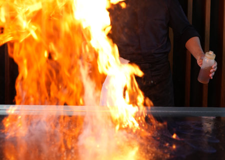 Chef cooking at stove with fire flame, close-up, selective focus. Chef cook food with fire at kitchen restaurantの写真素材