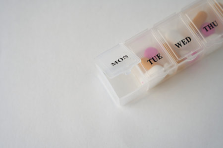 Daily pill box with medications and nutritional supplements on a white background with copy space. Medical pills organizerの写真素材