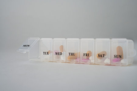 Daily pill box with medications and nutritional supplements on a white background with copy space....