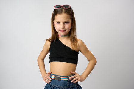 Cute girl portrait on a white background, close-up. Child girl with makeup wearing summer clothes, denim skirt and sleeveless topの写真素材