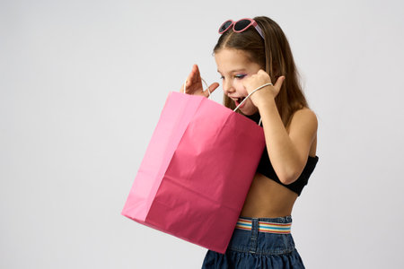 Portrait of a surprised beautiful girl wearing summer clothes and sunglasses holding shopping bags isolated over white background.の写真素材