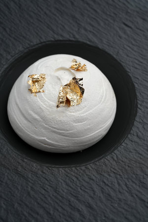 Pavlova dessert, meringue cake on a black plate on marble background, close-upの写真素材