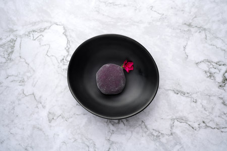 Traditional japanese mochi dessert with currant. Mochi ice cream on a black plate, marble background...