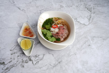 Pho Bo vietnamese soup with beef and noodles on a marble background, top view