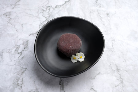 Traditional japanese mochi dessert with currant. Mochi ice cream on a black plate, marble background...