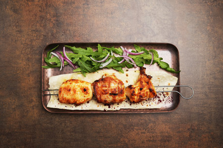 Grilled chicken on skewer served on tray, close-upの写真素材