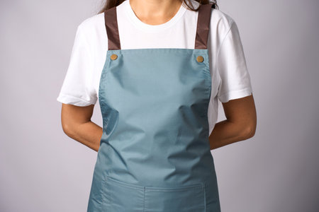 Young female wearing apron standing on a white background with copy space, close-upの写真素材