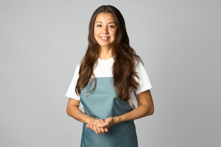 Portrait of young woman barista standing with arms crossed. Woman wearing apron and white shirt, white backgroundの写真素材