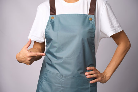 Female chef wearing apron and pointing with hand, close-up, standing on a white background. Can be used for restaurant menuの写真素材