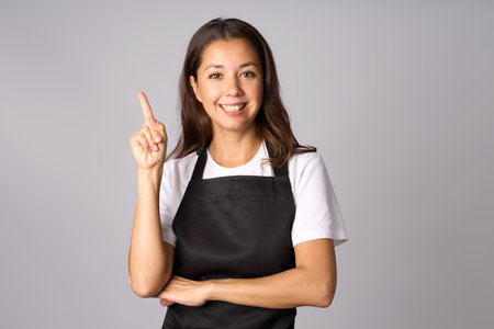 Young woman in black apron pointing with fingerの写真素材