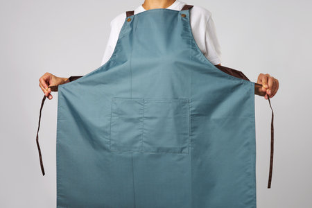 Young woman wearing apron standing. Female chef wearing apron, grey backgroundの写真素材