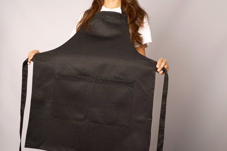 Young woman wearing apron standing. Female chef wearing apron, grey backgroundの写真素材