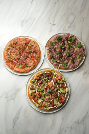 Top view of three pizza on a marble table background with copy space. A pizza restaurant