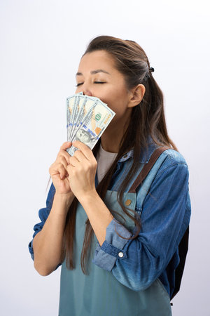 Young woman barista in apron holding cash money dollar, white background with copy spaceの写真素材