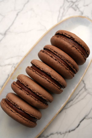 Chocolate macaron dessert. Brown macaroon with chocolate cream on a white plateの写真素材