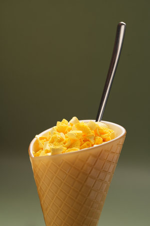 Melon ice cream cone with marshmallow and spoon on green background with copy space