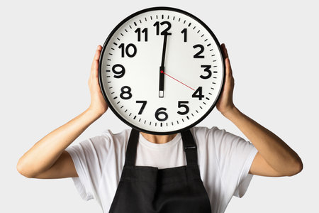 Cooking deadline concept. Woman chef in apron holding clock, white background with copy spaceの写真素材