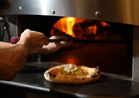 A pizza is being cooked in a wood fired ovenの写真素材