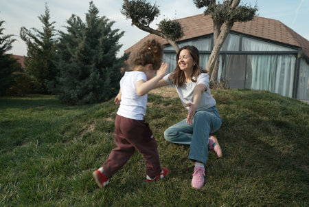 Playful Game Between Mother and Child Outdoors. A woman and her young daughter are playing a game of...