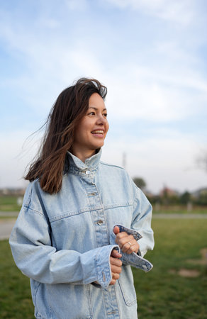 Low-Angle Portrait of a Woman Looking Up at the Sky. A woman with long brown hair and freckles, wearing a light blue denim jacket, is seen from a low angle, looking upwards towards a bright skyの写真素材