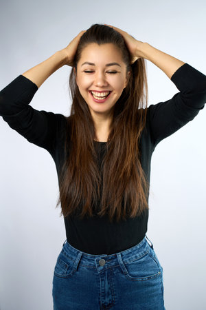 Portrait of Beautiful Smiling Young Woman. A gorgeous woman with long brown hair against a plain light grey backdropの写真素材