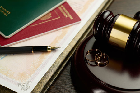 Close-up of a divorce decree or legal document, two golden wedding rings, judge gavel, two passports and a fountain pen. Legal process of divorce, the separation of a marriage, honeymoon and travelの写真素材
