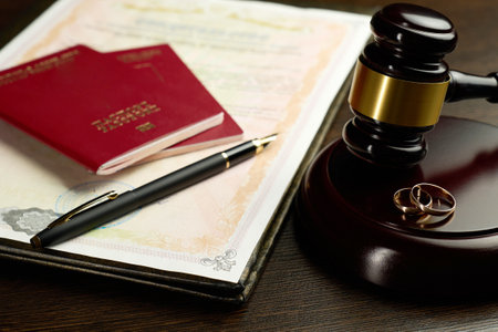 Judge gavel, legal document divorce decree, two golden wedding rings, passports and a fountain pen. Legal dissolution of a marriage with international aspects, such as divided assets or relocationの写真素材