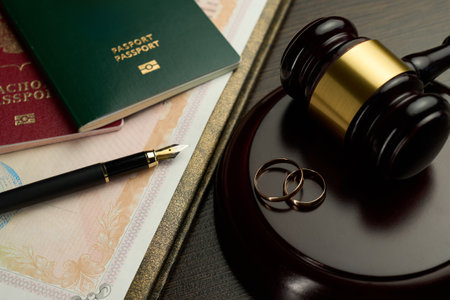 Close-up of a divorce decree or legal document, two golden wedding rings, judge gavel, two passports and a fountain pen. Legal process of divorce, the separation of a marriage and travelの写真素材