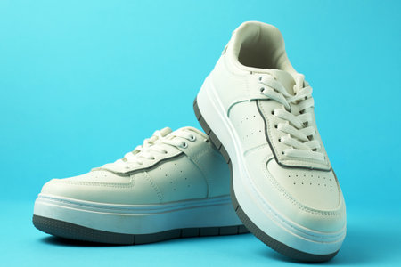 Close-up of a pair of white sneakers arranged on a blue background with copy space. Sneakers are clean, represent fashion footwear, streetwear style, athletic sports shoesの写真素材