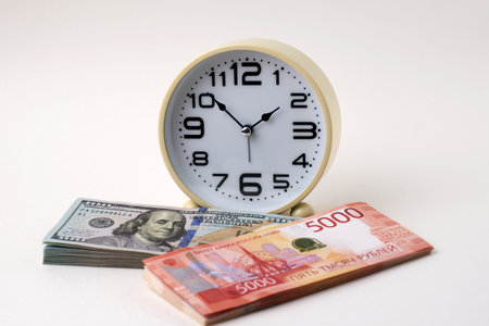 Close-up of desk clock stack of Russian Ruble banknotes and US Dollars Exchange. Time is money and importance of financial efficiency. Business, finance, productivity, and wealth management themesの写真素材