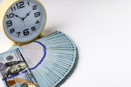 Close-up of alarm clock and stack of US dollar banknotes. Concept of time is money and the importance of financial efficiency. Business, finance, productivity, and wealthの写真素材
