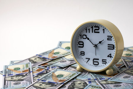 Close-up of alarm clock and stack of US dollar banknotes. Concept of time is money and the...