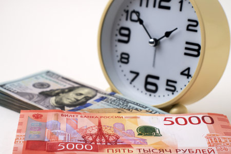 Close-up of desk clock stack of Russian Ruble banknotes and US Dollars Exchange. Time is money and importance of financial efficiency. Business, finance, productivity, and wealth management themesの写真素材