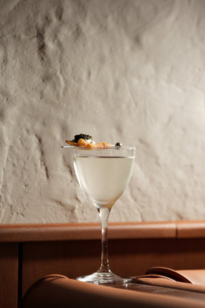 Close-up cocktail glass, garnished with a piece of fried or fruit topped with a white cream and black caviarの写真素材