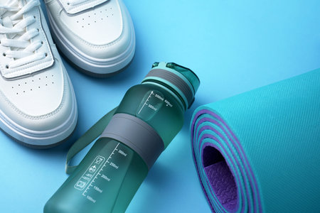 Fitness gear including a sports water bottle, running sneakers, and an exercise mat. Active lifestyle, home workout, healthy habits, and physical training. Gym preparation, cardio trainingの写真素材
