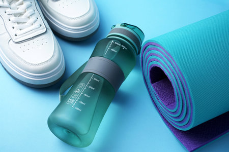 Fitness gear including a sports water bottle, running sneakers, and an exercise mat. Active lifestyle, home workout, healthy habits, and physical training. Gym preparation, cardio trainingの写真素材