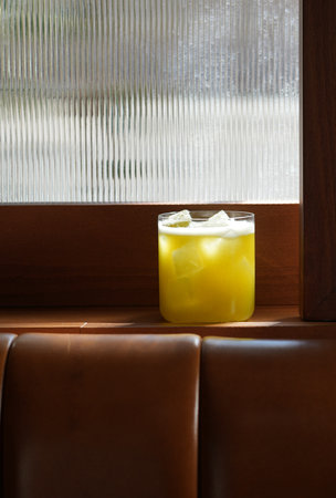 Vibrant yellow cocktail served in a rocks glass filled with ice. The drink has a frothy, white top, sour cocktailの写真素材