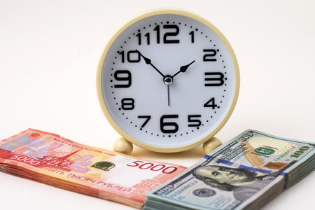 Close-up of desk clock stack of Russian Ruble banknotes and US Dollars Exchange. Time is money and importance of financial efficiency. Business, finance, productivity, and wealth management themesの写真素材