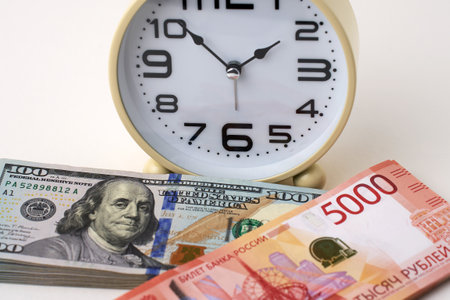 Close-up of desk clock stack of Russian Ruble banknotes and US Dollars Exchange. Time is money and importance of financial efficiency. Business, finance, productivity, and wealth management themesの写真素材